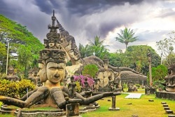 Mystic tropical garden with hindu and buddhist mythological creatures stone sculptures, storm clouds - Buddha Park (Wat Xieng Khuan), Vientiane, Laos 