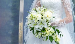 The bride in a white wedding dress is holding a wedding bouquet. 