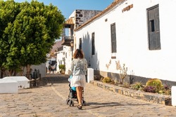 A young mother walking next to the white church of Betancuria, west coast of the island of Fuerteventura, Canary Islands. Spain
