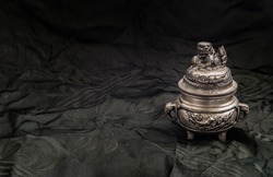 Sculpture engraved decorate on Small silver ancient incense burner on dark background. Antiques, Copy space, Selective focus.