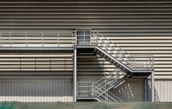Side view of an external metal staircase as an Fire escape route at modern warehouse building. Interesting architectural elements, Emergency exit concept, Selective focus.