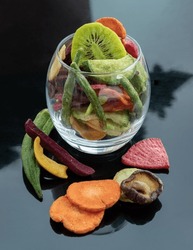 Different colorful dried fruits and vegetables in the glass. Crispy mixed veggies and fruits, Healthy snacks food, Space for text, Selective focus.