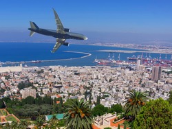The plane with tourists flies over the sea coast. City of Haifa. Israel.