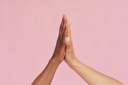 Hands of Caucasian man and black African American giving each other five on pink background. The concept of racism and all lives matter