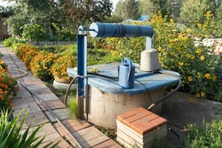 Blue Ancient artesian well from an iron tank in the garden. well in the garden, saving water in times of drought