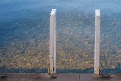 White handrail , concrete dock pier. Water surface. Sunlight. Ohrid lake Macedonia 2023. 
