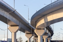 Fragment of a new road junction, bottom view. Overpasses on concrete supports. High-speed movement of vehicles in the city. Construction of express roads