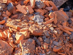 A pile of broken red bricks - the remains of a destroyed building. Broken bricks close up. Demolition or destruction of buildings. Construction debris