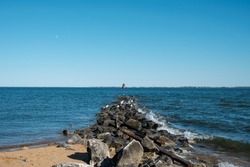 A beach that has a bunch rocks and a buoy can be seen in the sea.