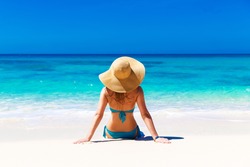  Young girl in a straw hat on a tropical beach. Summer vacation concept.