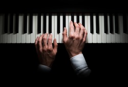 Isolated hands playing on the piano, dark background