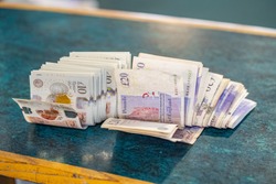 a bunch of bundled plastic ten pound notes and paper cotton twenty pound notes sitting on a wooden counter top