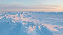Winter arctic landscape. View of snow and ice at sunset. Ice hummocks on the frozen sea in the Arctic. Cold frosty winter weather. Harsh polar climate. Travel and hikes to the far north to the Arctic.