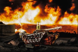 glass bottle made in the form of a tank stands on coals, against the background of a burning flame and tongues of fire, visualization of hostilities