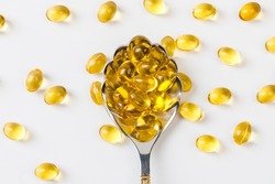 Close up of  oil filled capsules suitable for: fish oil, omega 3, omega 6, omega 9,  vitamin A, vitamin D, vitamin D3, vitamin E with a spoon 