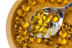 Close up of  oil filled capsules suitable for: fish oil, omega 3, omega 6, omega 9,  vitamin A, vitamin D, vitamin D3, vitamin E with a spoon 