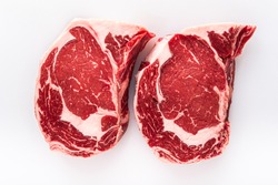 Two freshly cut boneless ribeye steaks on a butchers table