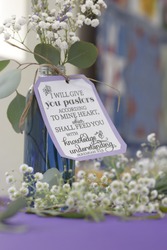 A close up of a vase filled and surrounded by baby breath flowers. On the vase is a sign with a Bible verse about pastors from the Book of Jeremiah.
