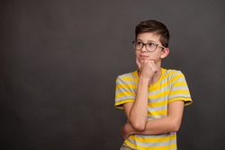 A teenage boy with glasses thought about it. Serious face expression. copy space