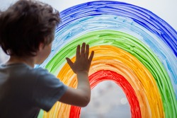 Chase the rainbow. child at home draws a rainbow on the window. Autism Awareness Day, 2 April.  quarantine pandemic coronavirus. Children create artist paints creativity vacation