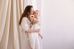 mother in white clothes kiss a baby. Purity innocence sanctity of motherhood. Mom and child. happiness of motherhood. Eco parenting vegan. Closeness to nature. Happy childhood care. Natural fabric