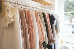Beautiful female wardrobe. A lot of party dresses hanging on hangers in closet. Vintage clothing rental concept. Women's space.  Boho market. Small boutique showroom fashion shop. big choice