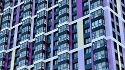 The facade of the building in purple,geometric patterns from windows and balconies, the colored wall of a modern multi-storey residential building, the abstract texture of the facade of the house