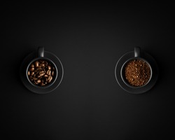 Two black cups with ground coffee and coffee beans. Cups with saucers on black background. View from above.