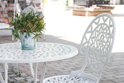 white table and wrought iron chair at a street cafe