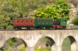 Model of locomotive pushing carriages on a concrete viaduct bridge