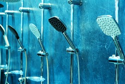 Shower heads hang on a wall in a plumbing store. Trade in modern equipment for bathtubs