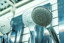 An assortment of shower heads in a plumbing store. Nozzles of different types and shapes on the showcase. Close-up