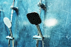 Shower heads in a plumbing store hang on a blue wall. Copy space