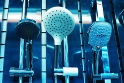 Shower heads of different shapes in the window of a plumbing store. Close-up