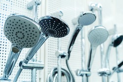 Shower heads of different sizes and shapes in the assortment of the retail network. Sale of bathroom equipment in a specialized store. Close-up