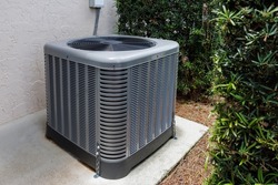 Modern HVAC air conditioner unit on concrete slab outside of house. 