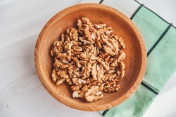 Walnuts in a plate on a brown wooden background. Nuts are a source of vegetable protein.