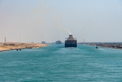 Suez Canal, panorama view of the canal with blue water and transiting ship on the horizon.  