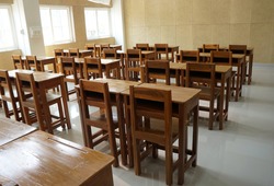 Student desks and chairs are arranged neatly in the classroom.