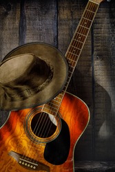 acoustic guitar and cowboy hat on wooden background