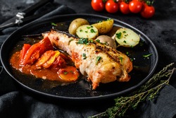 Cooking in tomatoes monkfish fish with baked potatoes. Fresh seafood. Black background. Top view