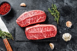Raw organic meat Twagyu oyster top blade steak. Black background. Top view