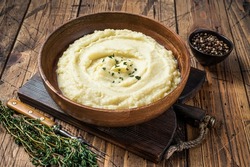 Mashed potatoes, boiled puree in a wooden plate. Wooden background. Top view