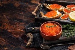 Toasts and Tartlets with Red caviar and butter in wooden tray. Wooden background. Top view. Copy space