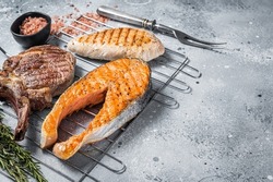 Set of bbq grilled meat steaks salmon, beef and turkey on a grill. Gray background. Top view. Copy space