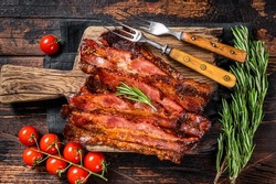 Roasted pork Bacon sizzling slices on wooden board. Wooden background. Top view