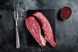 Bavette raw beef meat steak or Sirloin flap on marble board. Black background. Top view.