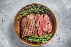Grilled sliced Skirt Steak on a plate with herbs. Gray background. Top view.