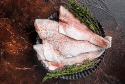 Raw ocean red perch fillet, Snapper fish with herbs. Dark background. Top view