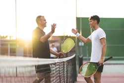 Father and Son Playing Tennis One to One. Family Doing Sport Together . Father Giving a Hug to His Son After Playing Tennis. Family Concept.